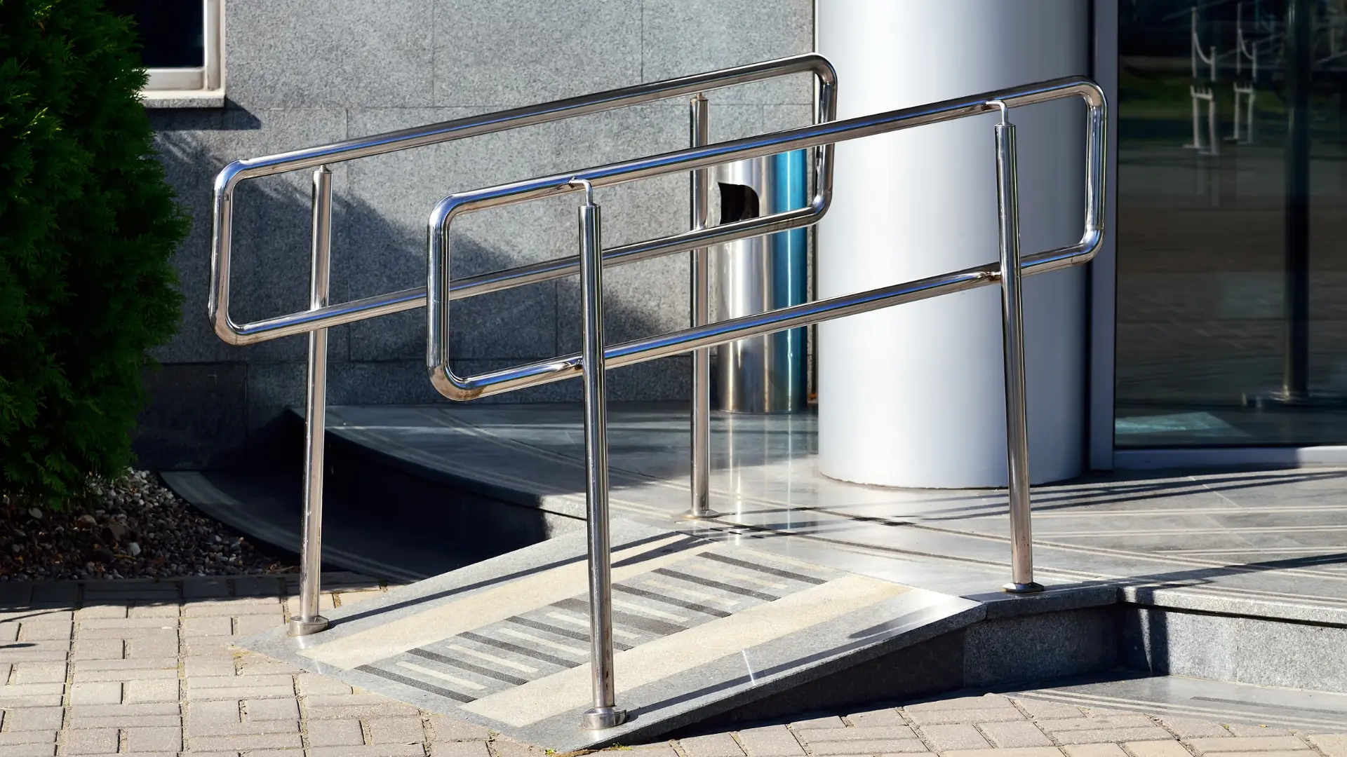Access ramp with stainless steel handrails leading to a level entrance
