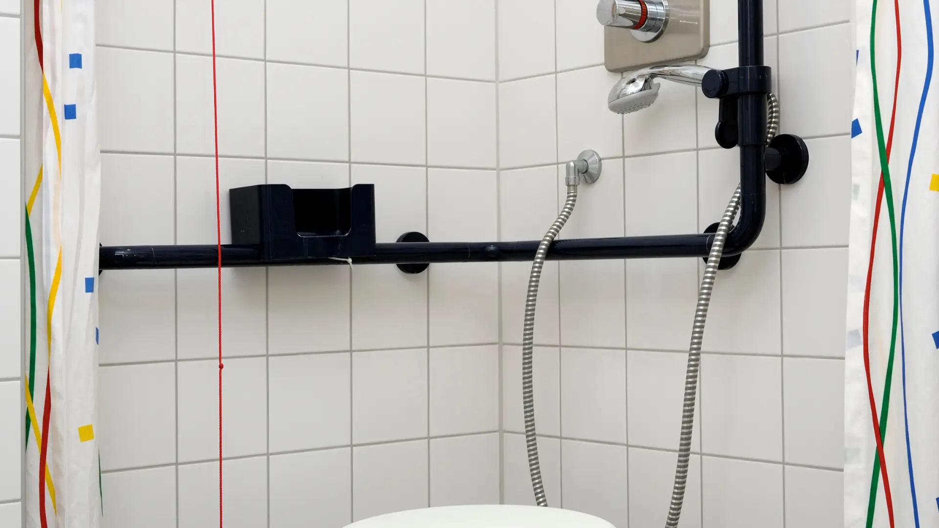 Walk-in shower with contrasting grab rail, shower controls and emergency pull cord
